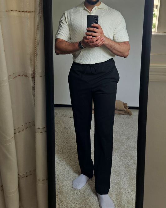 Person wearing a light-colored short-sleeve shirt and dark pants.